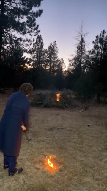 Percy beside a bonfire on a golf course at dusk